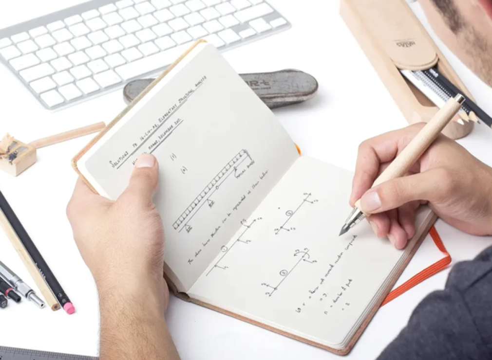 Peering over the shoulder of somebody sketching in a notebook